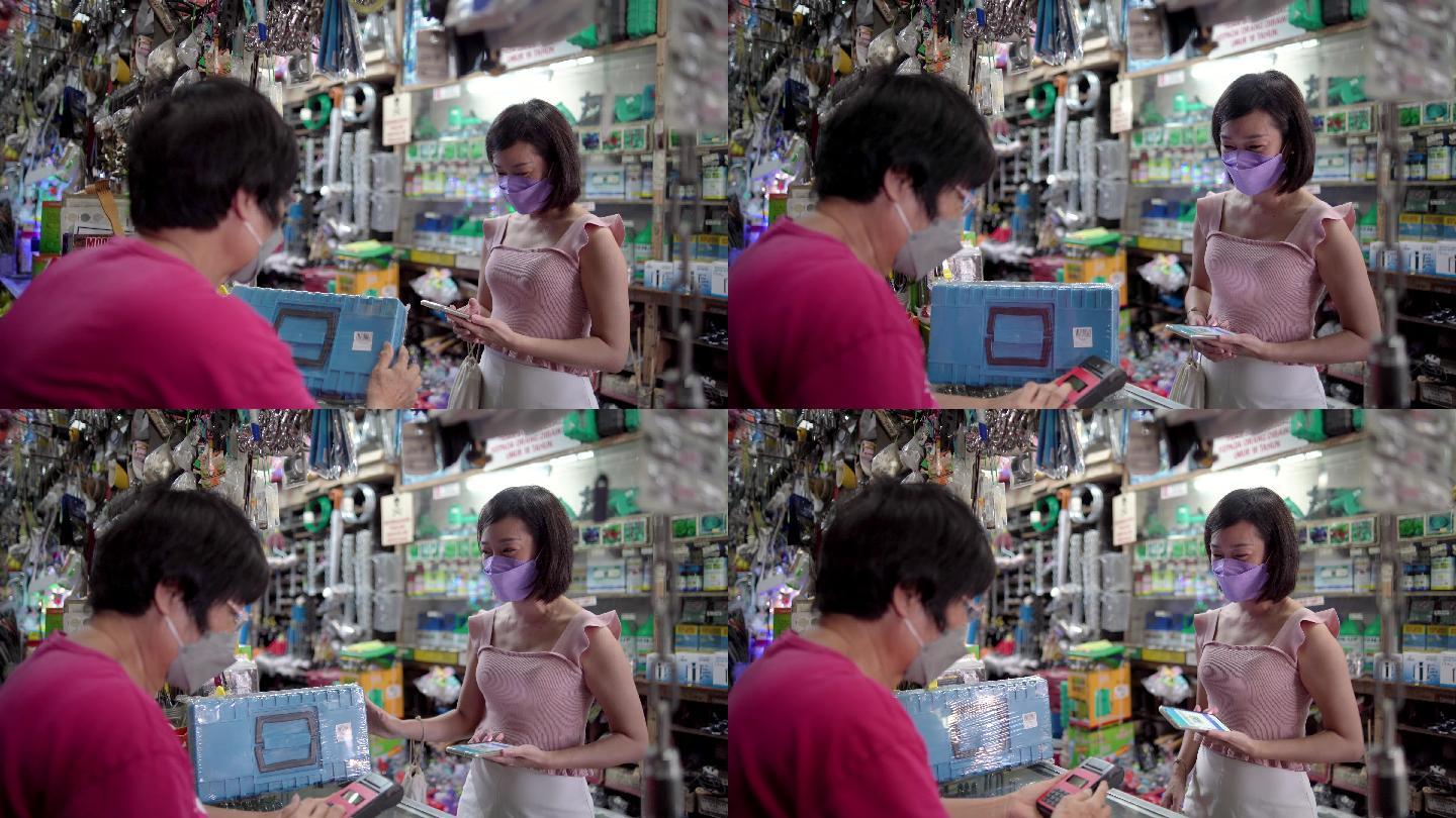 亚裔中国女性在商店购买硬件工具箱中用手机付款