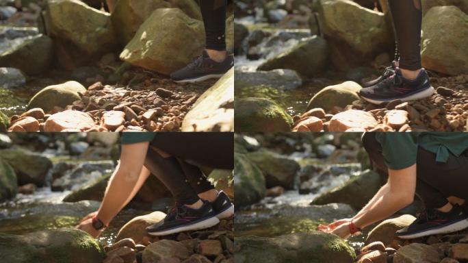 在森林中跑步时从溪流中喝水的健康女性