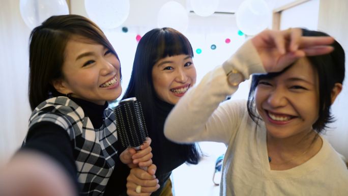 三名年轻日本女性在家唱卡拉OK时的电话视频