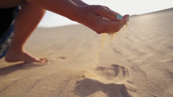 一个女人用沙子捧着双手的详细照片