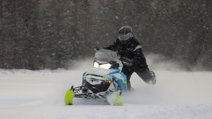 慢镜头：一名男子开着摩托雪橇在粉状雪地上疾驰