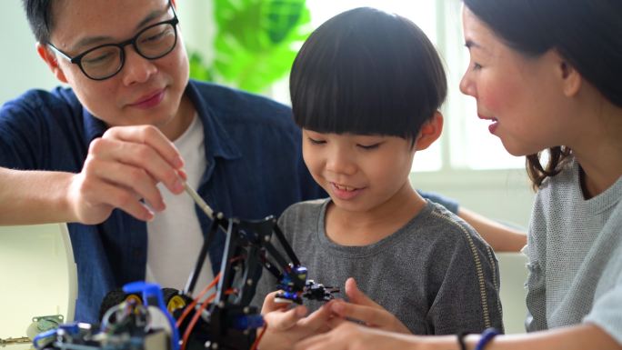 亚洲小男孩与父母一起制作机器人玩具