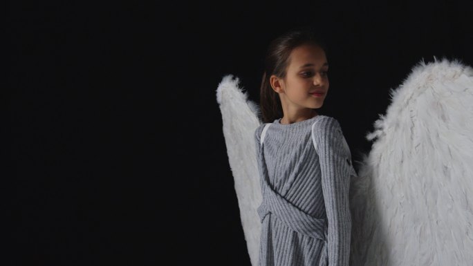 工作室拍摄了一个穿着天使翅膀的好奇女孩的肖像