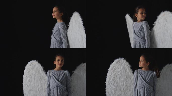工作室拍摄了一个穿着天使翅膀的好奇女孩的肖像