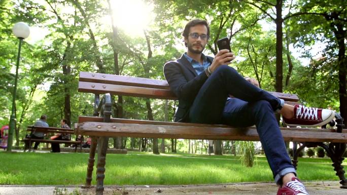 坐在公园里发短信外国人使用手机外国公园休
