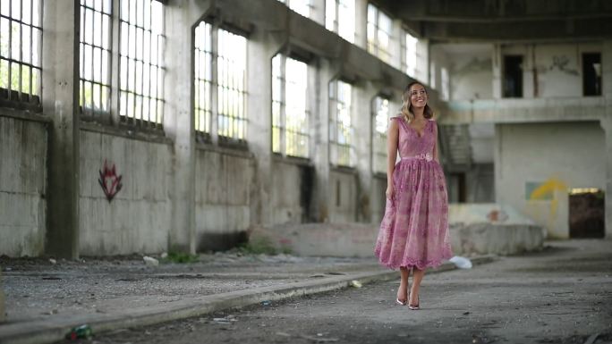 废弃仓库中穿着粉红色连衣裙的年轻女士
