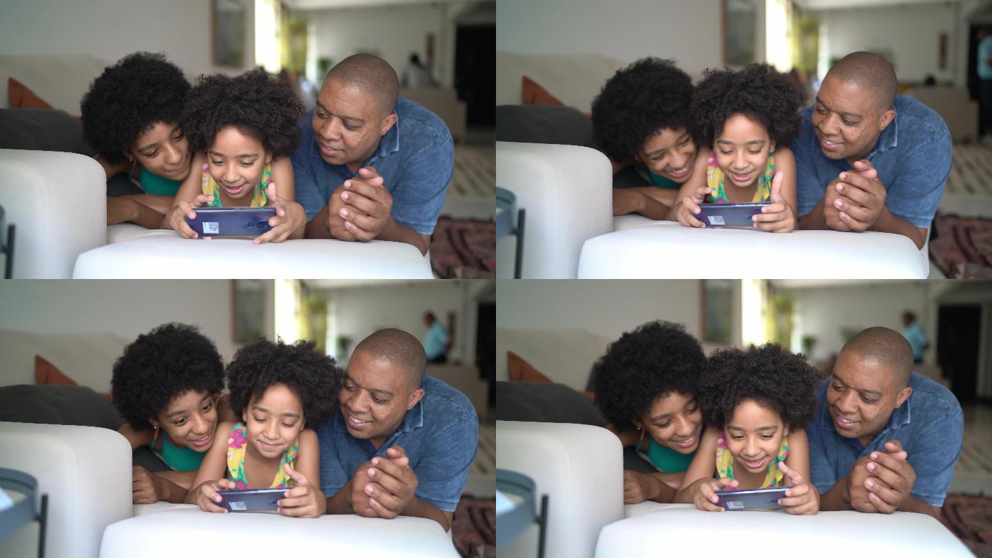 父亲和女儿一起使用智能手机躺在家里的沙发上