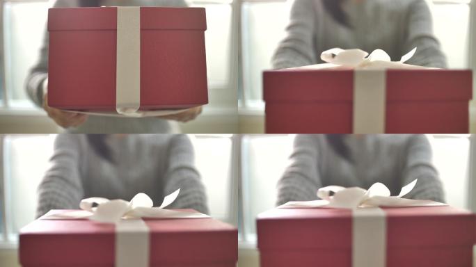女性将红色礼品盒放入相机