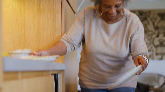 家中厨房使用洗碗机的老妇人
