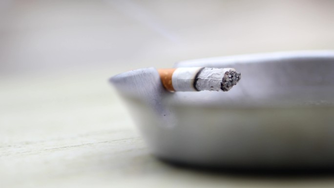 烟灰缸上燃烧的香烟特写图