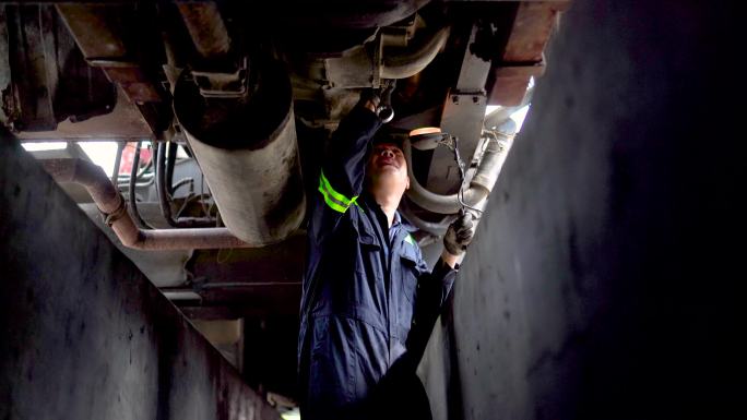亚裔中国机械师在修理厂使用扳手卡车底盘进行检查和调整