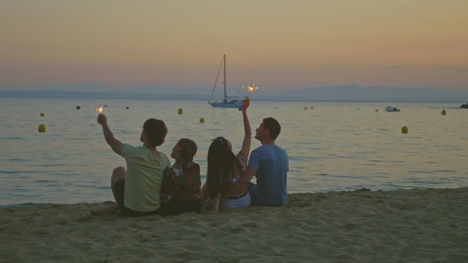 四个带着照明弹的朋友在海滩上看日落