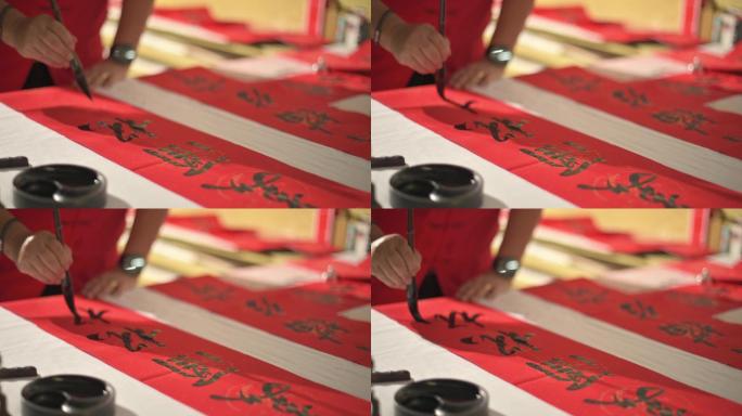亚裔中国男性为即将到来的中国新年庆祝活动练习汉字书法的手，将其写在一张红色的纸上，以繁荣和良好的措辞