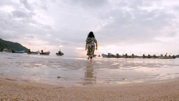 日出时分，一名女乘客站在海滩上跑步，伸开双臂呼吸新鲜空气，并举起双臂