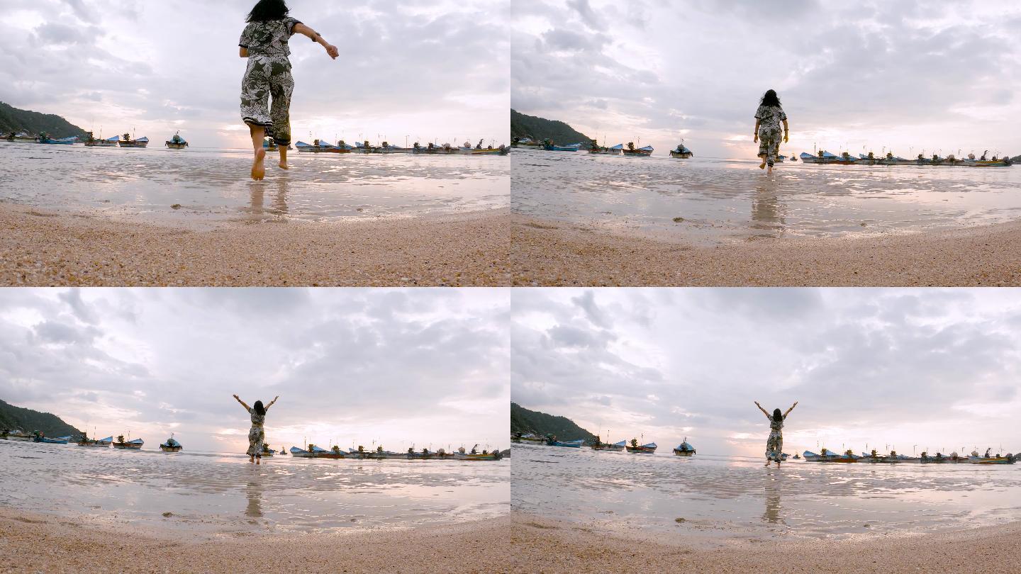 日出时分，一名女乘客站在海滩上跑步，伸开双臂呼吸新鲜空气，并举起双臂