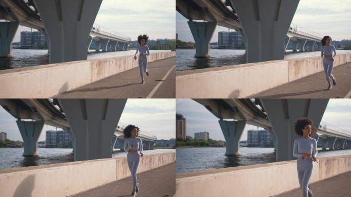 一位穿着白色慢跑服、留着黑色卷发、身材苗条的年轻跑步者在阳光明媚的日子里跑过摄像机