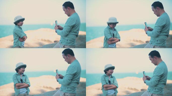 爸爸和儿子在海滩上用智能手机拍照