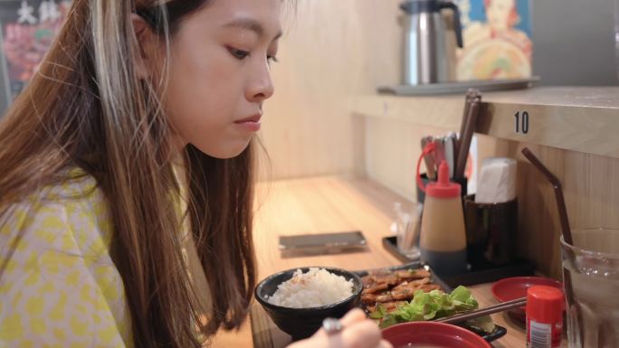 Genration Z微笑着的亚洲女性吃着涮涮涮或素烧，这是一道由猪肉、牛肉、虾、鱿鱼、海鲜和新鲜蔬