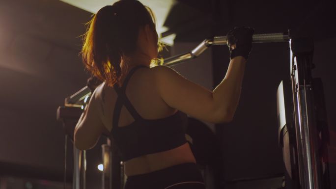 后视亚裔中国中年女运动员引体向上锻炼二头肌在健身房单杠常规锻炼中的牵引力