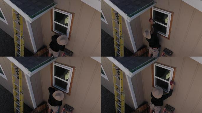 2名成年人在他们房子的二楼安装窗户4K视频无人机