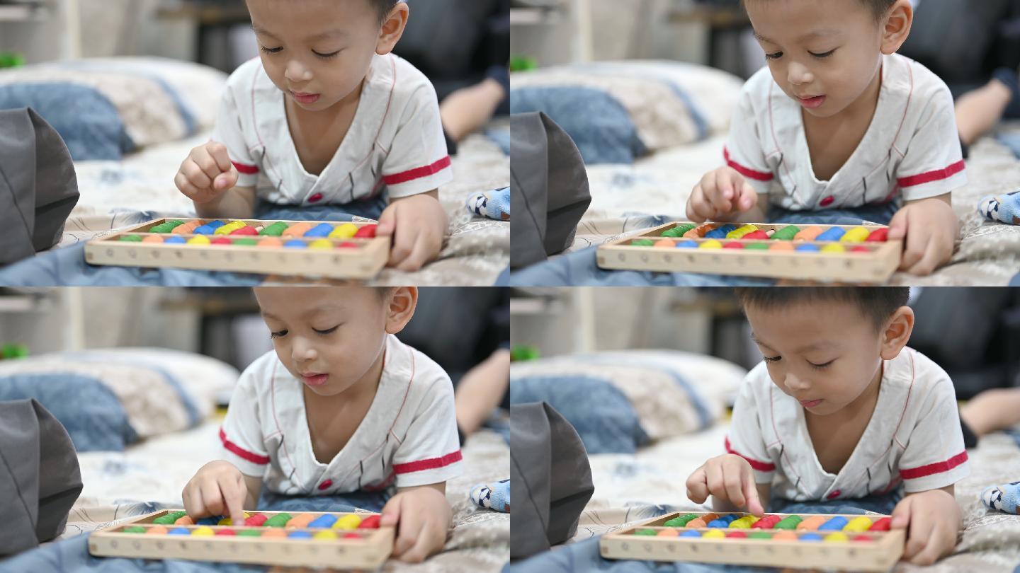 学龄前男婴学习数数。可爱的孩子在玩算盘玩具。小男孩在家里玩得很开心。