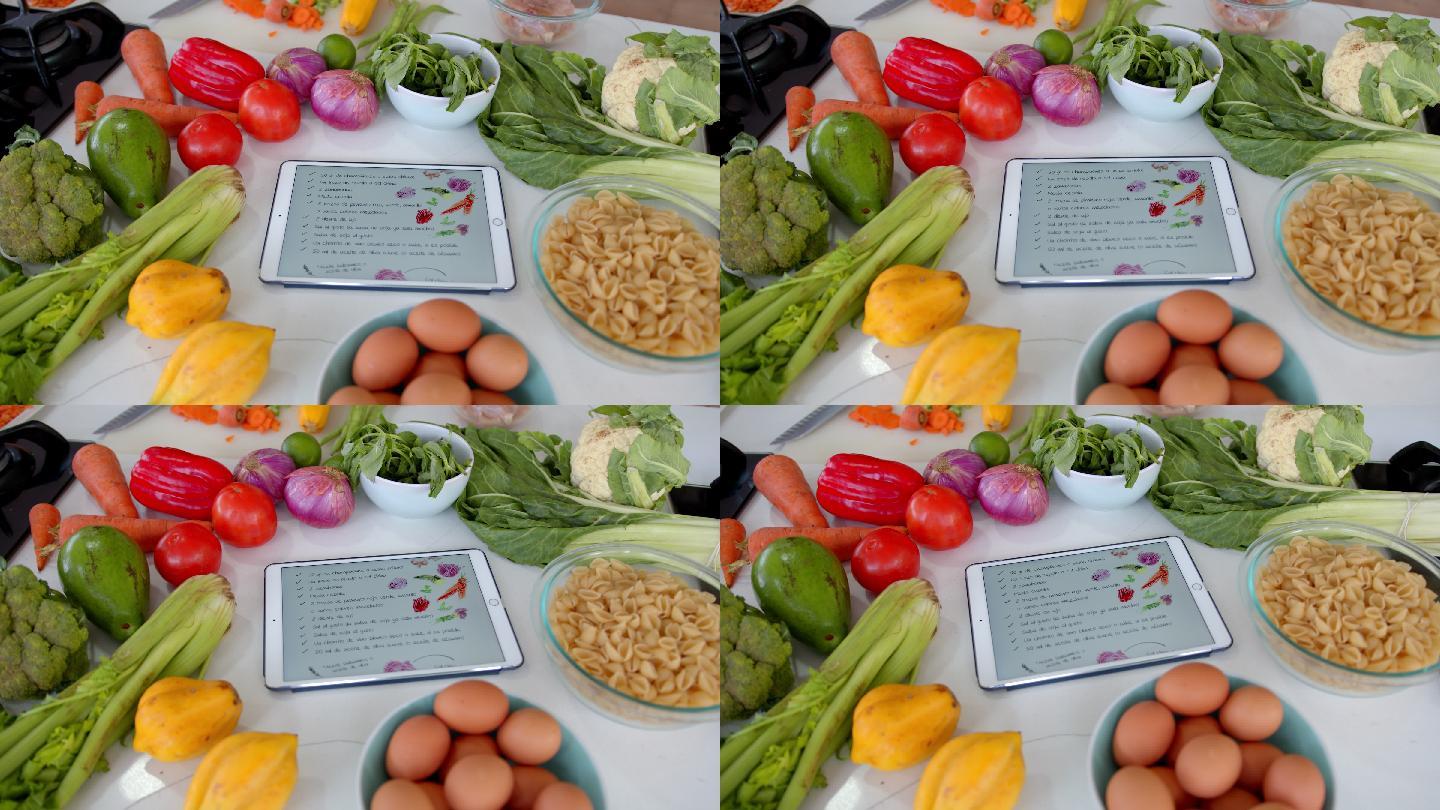 新鲜美味的蔬菜、鸡肉和意大利面食放在一块展示食谱的平板上，全部放在厨房柜台上