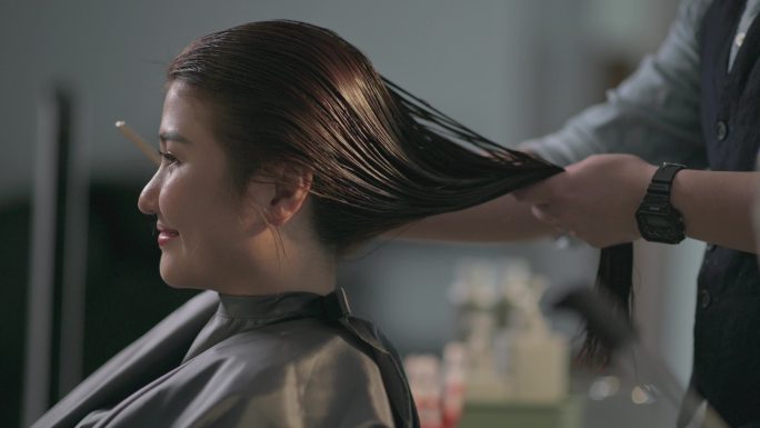 美发沙龙亚洲华人女发型师在美发沙龙为顾客剪湿长发
