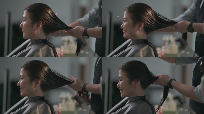 美发沙龙亚洲华人女发型师在美发沙龙为顾客剪湿长发