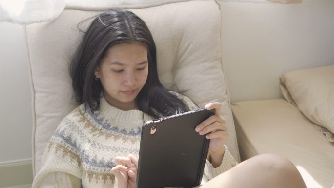 在棕色沙发上玩ipad的女人