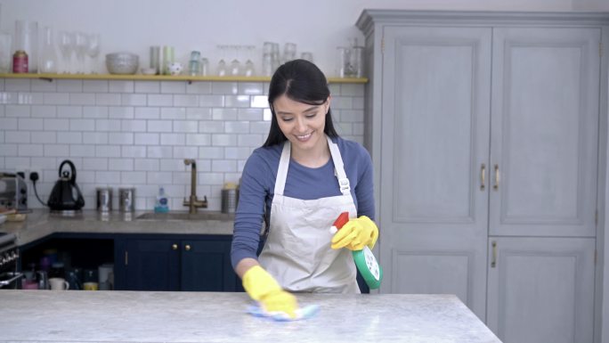 女人用抹布和喷雾清洁厨房柜台