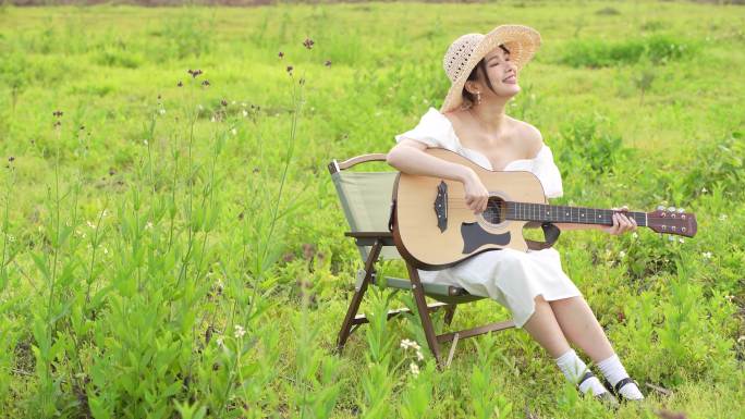 女孩在草原上弹凑吉他