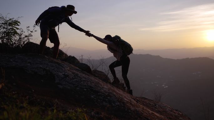 两个徒步旅行者在登山小道上帮助登上山顶