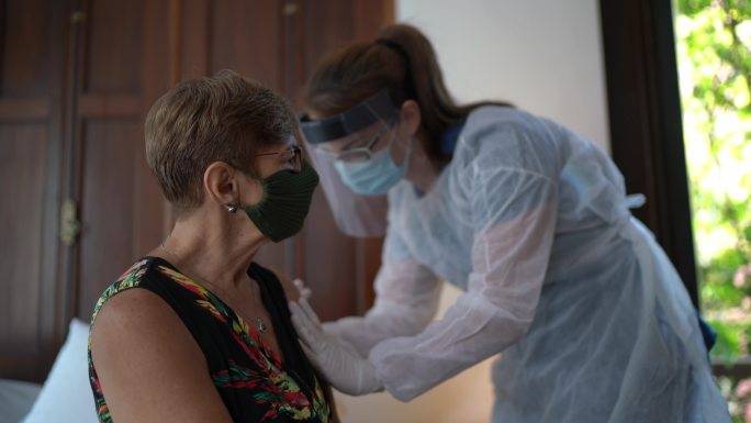 医生在家为老年妇女接种疫苗-戴口罩