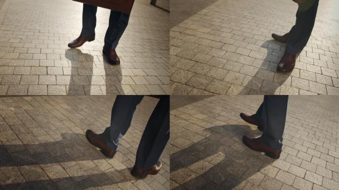 视频中，一位商人的脚穿着棕色皮鞋，在铺好的街道上左右移动，而相机在四处飞舞
