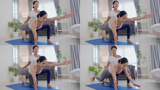 年轻活跃的运动型苗条亚洲女性，以板状姿势进行瑜伽锻炼，将腿向后伸展，手臂向前伸展，并由私人教练指导，