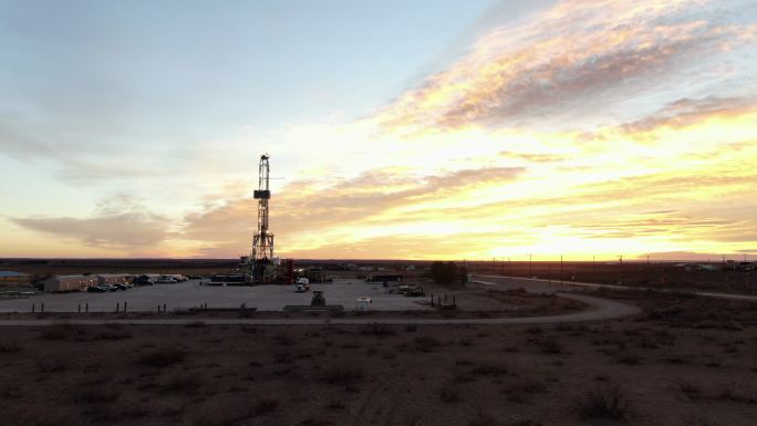 日落时分，在美丽的云层覆盖的天空中俯瞰石油或天然气钻井压裂井场