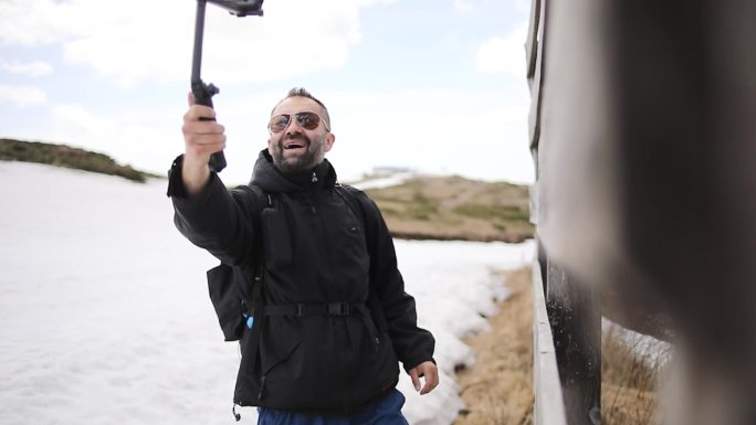这位徒步旅行者走上山，用他的gopro相机拍摄视频，为他的viode博客制作视频。他利用一个美丽的春