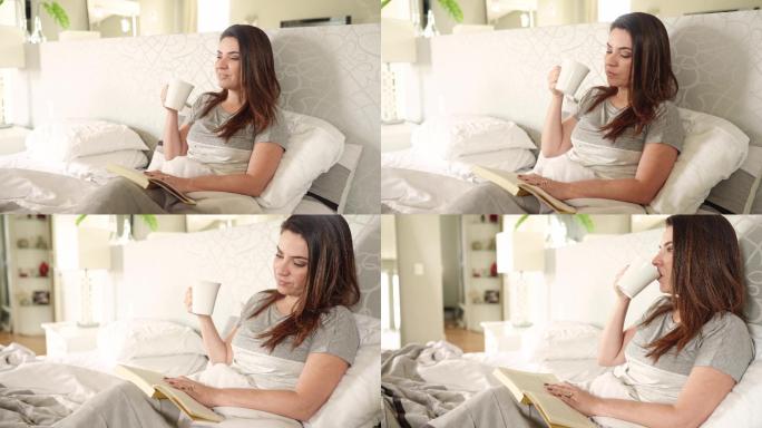 微笑的女人在床上一边喝咖啡一边看书