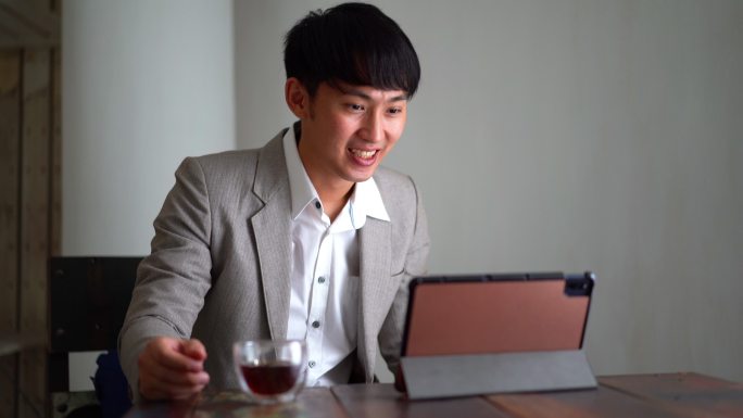 年轻的亚洲商人使用数字平板电脑与商业伙伴视频通话
