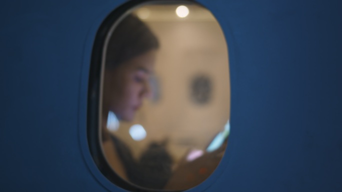 亚洲女性乘客在飞机上使用智能手机，从飞机窗外观看