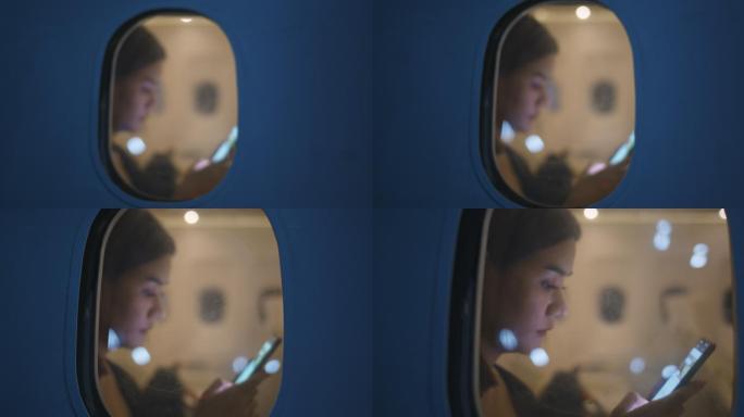 亚洲女性乘客在飞机上使用智能手机，从飞机窗外观看