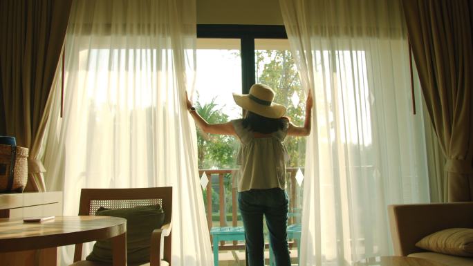 亚洲女旅行者住在一家酒店的房间里。打开房间里的窗帘和门。假期旅行概念。4k慢动作。