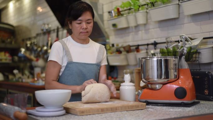 亚洲华人面包师妇女在厨房准备面团