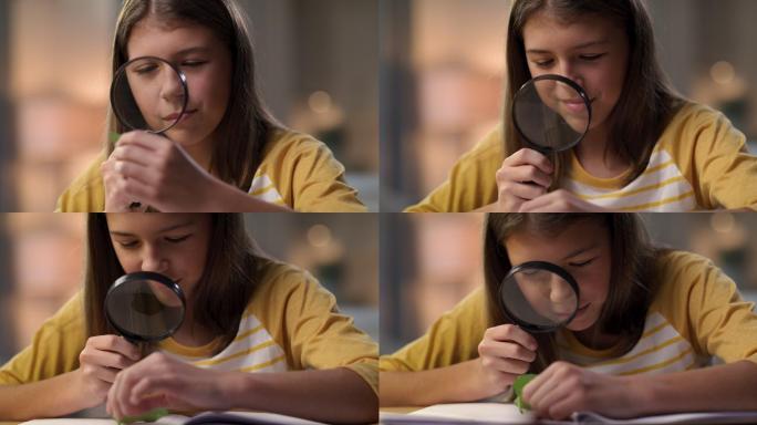 一个年轻女孩独自坐在家里，一边做科学作业，一边使用放大镜的4k视频片段