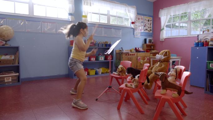 古巴女孩戴着面罩指挥玩具乐队