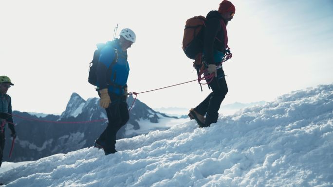 登山队登上山顶。带绳索和设备的冬季冒险