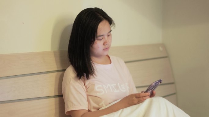 年轻女孩坐在床上玩手机刷朋友圈