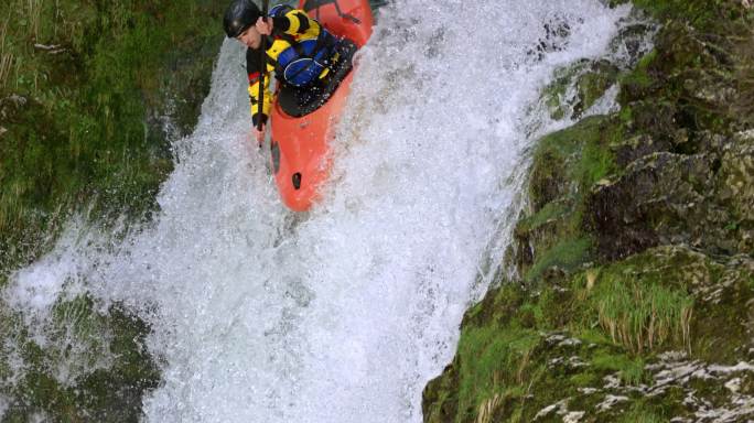 SLO-MO男子皮划艇运动员从瀑布上摔下来，头直冲入水垫池