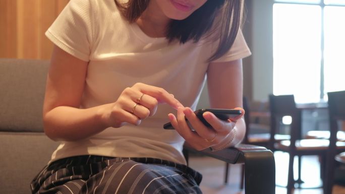 亚洲女性在咖啡馆使用智能手机进行社交媒体。