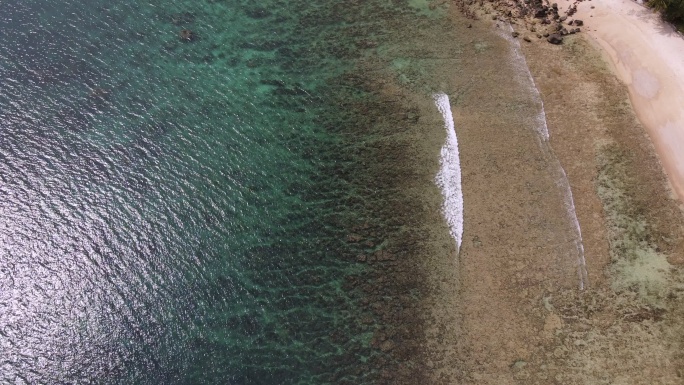 无人机俯瞰大海和海滩上的岩石，泰国在清澈的蓝色海水上飞行，在海面上拍摄到令人惊叹的低空航拍。股票视频